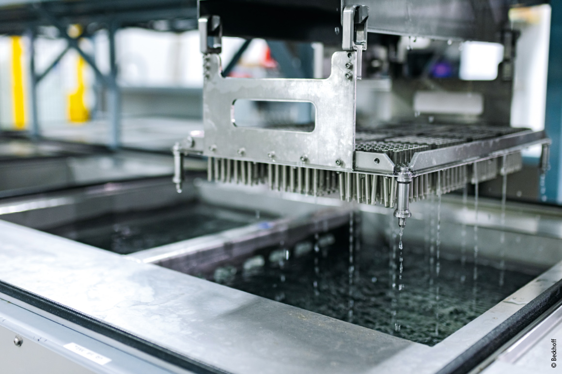 A gantry moves trays of product through various baths before and after machining.