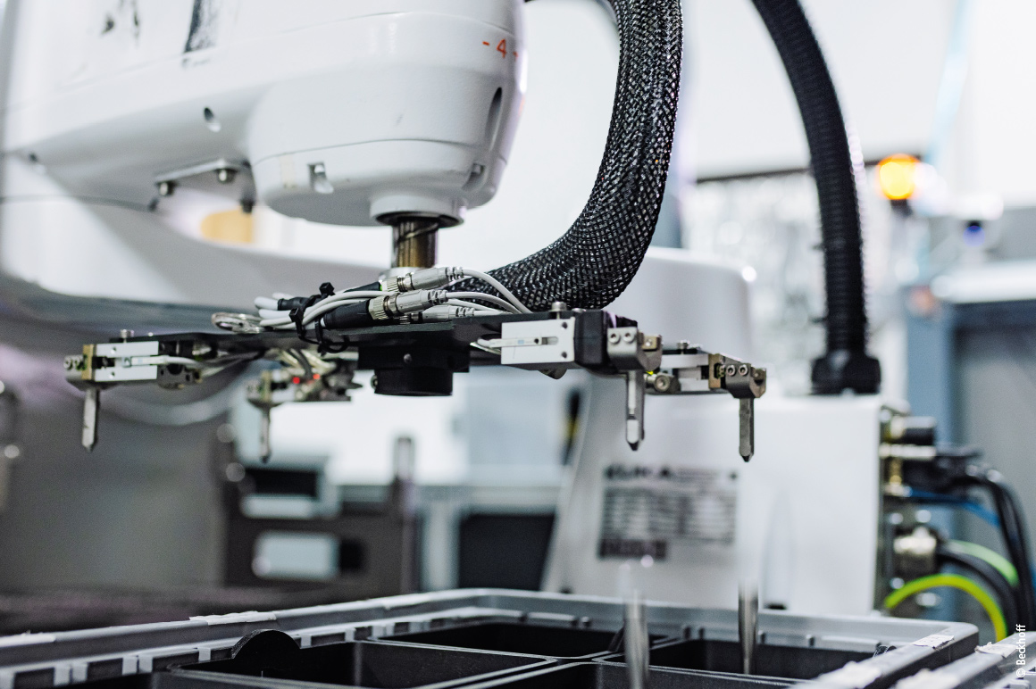 A SCARA robot unloads trays of product and routes pieces for inspection.